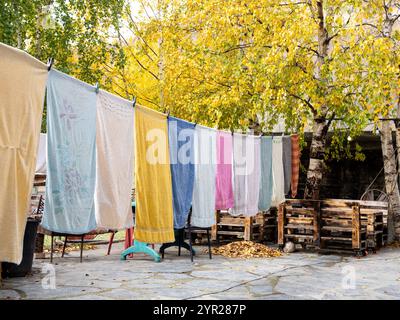 Viele bunte Handtücher hängen in der Herbstsaison Wäsche auf der Wäscheleine im Außenbereich. Wäscheleine mit frisch gewaschener Kleidung im Freien zu Hause Stockfoto
