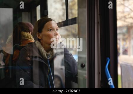 Traurige und besinnliche Frau, die mit einem schmutzigen Bus durch die Straßen der Stadt fährt, selektiver Fokus Stockfoto