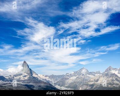 Panoramaszene des Matterhorns und vieler Gipfel der Schweizer Alpen. Fantastischer Blick auf Matterhorn auf hellblauem Himmel und Wolkenhintergrund. Touristenziel Stockfoto