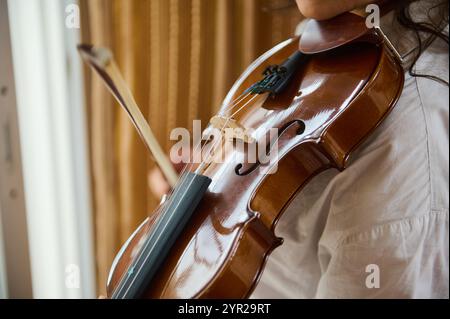 Eine Nahaufnahme, die sich auf eine Person konzentriert, die Geige spielt. Das Bild erfasst die eleganten Details des Instruments und die ausgeglichene Handposition, Highli Stockfoto