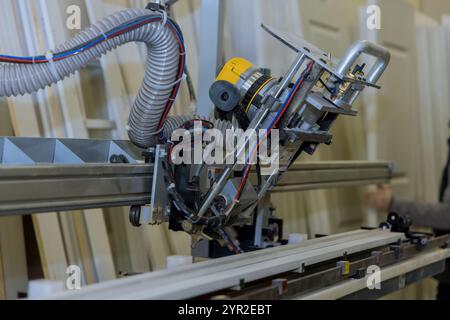 Holzbearbeitungsmaschine im Werk, die ein automatisches Schneidebohrwerkzeug zeigt, das für Tür mit angeschlossenem Schlauch für Staubabsaugmaschine verwendet wird Stockfoto