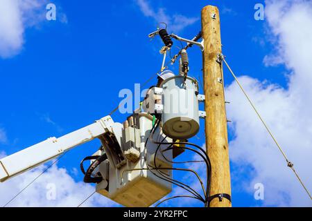 Kommunaler Kraftarbeiter im hydraulischen Hubwerk führt eine Inspektion der Hochspannungsanlagen durch. Stockfoto