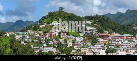 St. George's, Grenada - 4. Januar 2018: Panoramablick auf farbenfrohe Hügelhäuser und üppiges Grün unter teilweise bewölktem Himmel. Stockfoto