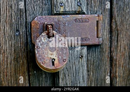 Rostiges Vorhängeschloss an rauer Holztür Stockfoto