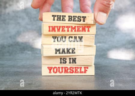 Die beste Investition, die Sie tätigen können, ist, in sich selbst zu investieren. Zitat zur Motivation. Positive Affirmation. Geschrieben auf Holzblöcken mit dunklem Hintergrund. Stockfoto