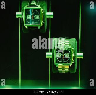 Baden-Baden, Deutschland - 1. Dez. 2024: Nahaufnahme zweier luxuriöser TAG Heuer Monaco Uhren mit markanter grüner Beleuchtung, zeitlosem Design und handwerklichem Können Stockfoto