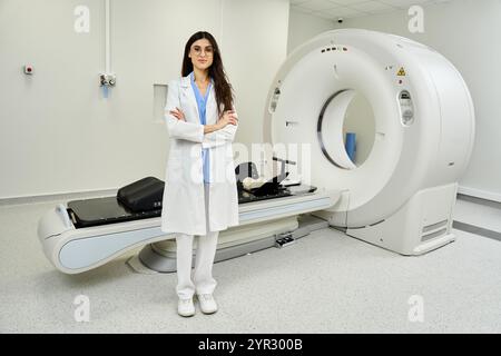 Attraktiver Arzt steht zuversichtlich neben fortschrittlichen MRT-Geräten und ist bereit, die Diagnostik zu verbessern. Stockfoto