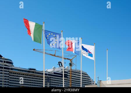 Marseille. Frankreich - 02. Dezember 2024: Zeigt Flaggen von Italien, der Europäischen Union und Frankreich und ein Kreuzfahrtschiff-Logo, das an einem Hafen fliegt, mit einer großen Kreuzfahrt Stockfoto