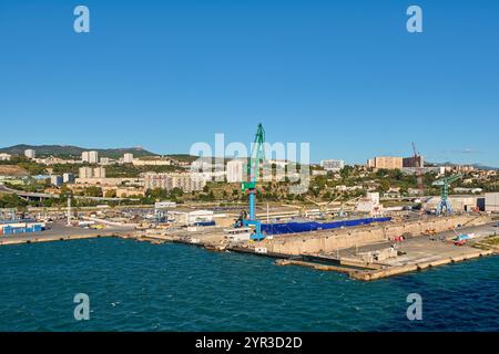 Marseille. Frankreich - 2. Dezember 2024: Ein lebhafter Tag im Hafen von Marseille, mit einer Fähre und einem Kreuzfahrtschiff, mit der Stadtlandschaft und den Bergen c Stockfoto