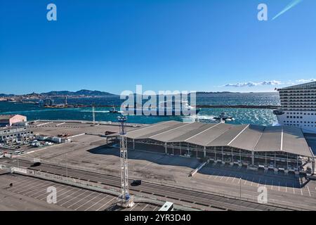 Marseille. Frankreich - 2. Dezember 2024: Ein klarer Tag im Hafen von Marseille, mit einer Fähre und einem Kreuzfahrtschiff, mit der Stadtlandschaft und den Bergen in der Stockfoto