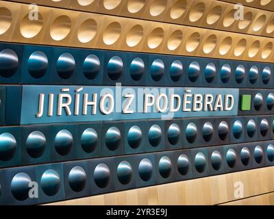 U-Bahn-Station Jiřího z Poděbrad in Prag, Tschechien. Zeichen des Standortnamens im U-Bahn-Tunnel. Gelbe und blaue Aluminiumformen befinden sich an der Wand. Stockfoto