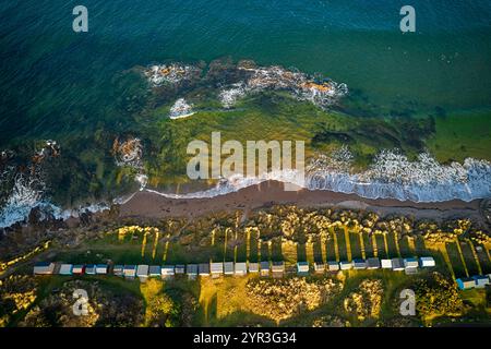 Hopeman Moray Coast Schottland bricht das Meer auf Felsen und Reihen von farbigen Strandhütten oder Chalets in der Wintersonne Stockfoto