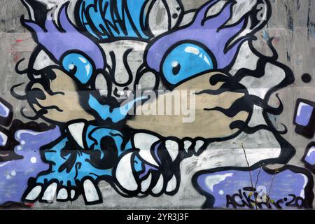 Graffiti, Inschrift, Zeichnung des Kopfes einer bösen Katze, eines Tigers von blau, lila, weiß, pfirsichfarben mit großen weißen Zähnen, schwarzen Barthaaren. Stockfoto
