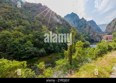 Eine Betonmauer, die sich um den künstlichen See des Matka Canyon mit Blättern und Trümmern dreht und auf der Wasseroberfläche schwimmt, und einen Metallsteg Stockfoto
