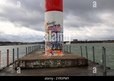 Charlotte, NY, USA - 23. November 2024 - ein Mann benutzt den Leuchtturm, um den Wind zu blockieren, während er aus seiner Pfeife raucht Stockfoto