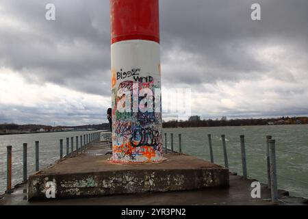 Charlotte, NY, USA - 23. November 2024 - ein Mann benutzt den Leuchtturm, um den Wind zu blockieren, während er aus seiner Pfeife raucht Stockfoto