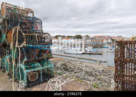 Boote im Yachthafen mit dem Meer dahinter und Hummertöpfe an der Hafenmauer, Anstruther, Fife, Schottland Stockfoto