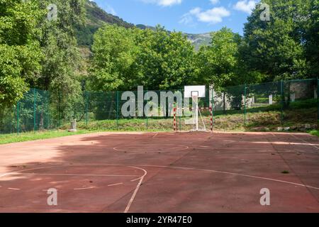 Ein Basketballkorb mit einem robusten roten Rand und einem ordentlich hängenden weißen Netz wird von unten vor dem Hintergrund eines unberührten blauen Himmels erfasst. Stockfoto
