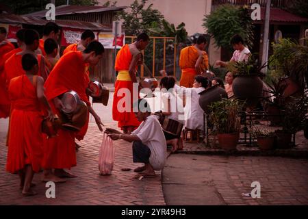 Luang Prabang, Laos – 9. April 2011: Die morgendliche Prozession der Mönche, beginnend um ca. 30 Uhr: Mönche und Novizen in Safrangewand steigen auf Stockfoto