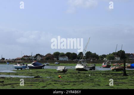 Emsworth, Hampshire, England. 26. August 2024. Boote im Hafen bei Ebbe mit entfernten Gebäuden am Horizont. Stockfoto