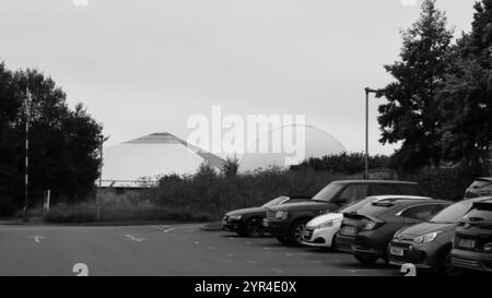 Winchester Science Centre and Planetarium, Winchester, England. 31. August 2024. Graustufen, Weitwinkelblick vom Parkplatz auf das pyramidenförmige Wissenschaftszentrum und das gewölbte Planetarium. Stockfoto