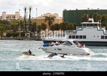 Miami, Florida, USA - 1. Dezember 2023: Person, die mit einem Jetski an einem Motorboot vorbeifährt und auf dem vorderen Deck sitzt Stockfoto