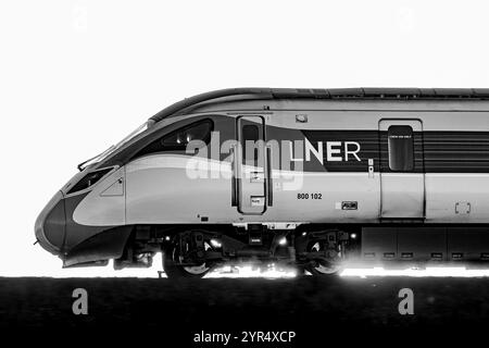 Monochrom Image of A LNER Azuma Train (800102), hintergrundbeleuchtet von Einem Sonnenuntergang, während er zwischen Dalmeny und Edinburgh Gateway Stations in Schottland Großbritannien fährt Stockfoto