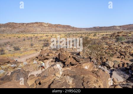 Touristen auf einem Wanderweg zu den Felsenstichen von Twyfelfontain, karge Landschaft in einem Tal, Twyfelfontain, Kunene, Namibia, Afrika Stockfoto