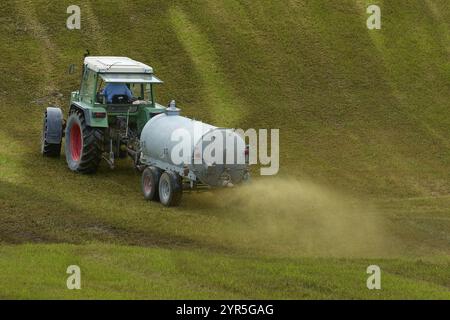 Traktor verteilt Gülle auf einem grünen Feld, Wiese, Bayern, Deutschland, Europa Stockfoto