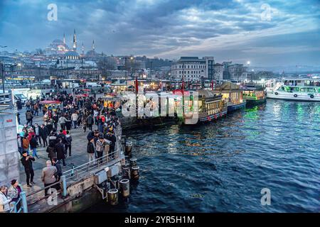 Istanbul - 9. Januar 2022. Die Fish Sandwich Boote liegen am Eminonu Pier an der Mündung der Golden Horn Bay und der Skyline des Eminonu District Stockfoto