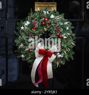 London, Großbritannien. Dezember 2024. Der Türkranz Nr. 10, ein Weihnachtskranz mit Kugeln und Weihnachtsdekorationen an der berühmten schwarzen Tür in der Downing Street 10, der offiziellen Residenz des britischen Premierministers und Regierungssitzes. Jedes Jahr wird ein Kranz an die Tür gelegt. Quelle: Imageplotter/Alamy Live News Stockfoto