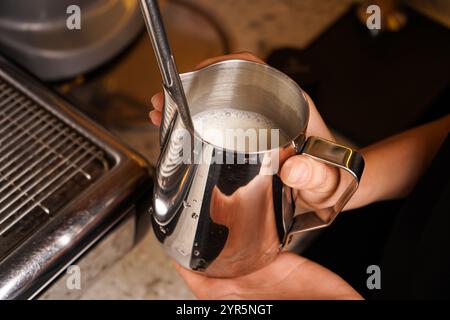 Ein Barista macht Kaffee in einem Café. Eine Tasse Cappuccino oder Latte wird vorbereitet. Nahaufnahme. Stockfoto