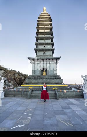 Eine Frau in einem roten Rock vor der Pagode des Kim Son Bao Thang Tempels auf dem Gipfel des Fansipan, dem höchsten Berg Vietnams Stockfoto