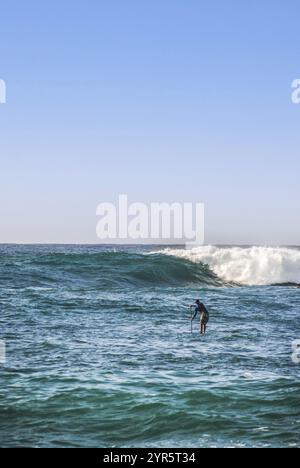 Ein Mann paddelt am Waimea Beach in Oahu, Hawaii Stockfoto