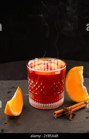 Aromatisches Punschgetränk und Zutaten auf einem Holztisch. Glühwein Rotwein mit Gewürzen und Orange im Glas. Hausgemachtes Weihnachtsgetränk. Stockfoto