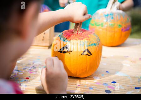 Ein Kind malt einen Kürbis für Halloween-Bastelaktivitäten Stockfoto