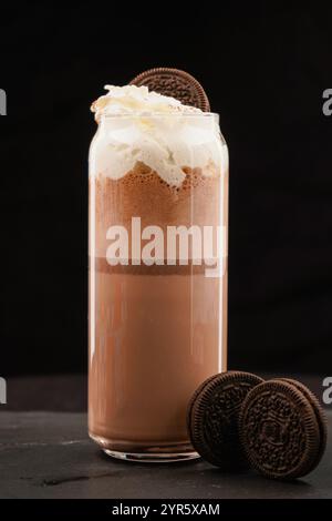 Schokoladen-Milchshake mit Stücken Schokoladenkekse. Auf schwarzem Hintergrund. Trinken Sie aus nächster Nähe. Stockfoto