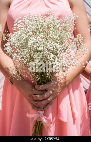 Brautjungfer hält Baby-Atem-Blumenstrauß in rosa Kleid Stockfoto