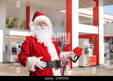 Der Weihnachtsmann hält eine Einspritzdüse an einer Tankstelle Stockfoto