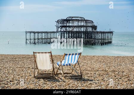 Zwei Klappstühle am Strand vor den Ruinen des Burnt Down West Pier in Brighton, East Sussex, England, Großbritannien Stockfoto