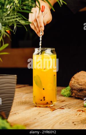 Margarita-Cocktail aus Mango-Passionsfrucht mit Minze und Limettenblättern. Ein tropisches alkoholisches Getränk für eine Sommerparty. Holzhintergrund, Kopierraum. Stockfoto