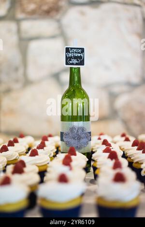 Weinflasche Herzstück mit mattierten Cupcakes auf rustikalem Hintergrund Stockfoto