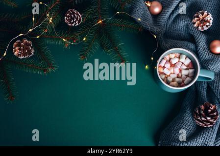 Heiße Schokolade mit Marshmallows, Tannenzapfen und Lichterketten auf dunkelgrünem Hintergrund. Gemütliche Weihnachtskulisse. Draufsicht, flach, Kopierbereich. Stockfoto