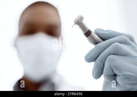 Nahaufnahme Des Schwarzen Arztes Des Zahnarztes In Der Medizinischen Maske, Die Zahnbohrmaschine Hält Stockfoto