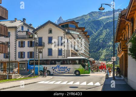 Blick auf das Zentrum der Bergstadt am Fuße des Mont Blanc-Massivs, mit einem Touristenbus und den Aiguilles du Dru im Sommer, Chamonix, Frankreich Stockfoto