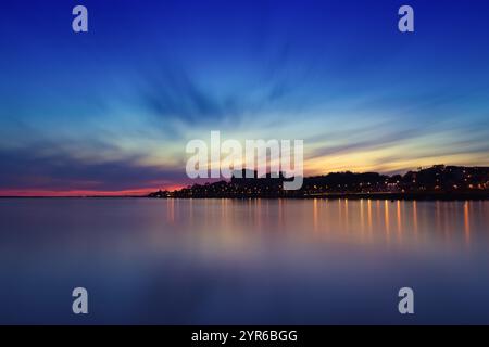 Farbenfroher Sonnenuntergang über dem Fluss douro in porto, portugal, mit Stadtlichtern, die sich auf dem ruhigen Wasser spiegeln und eine magische Atmosphäre schaffen Stockfoto