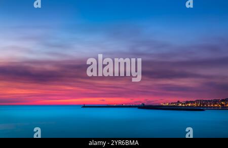 Der lebendige Sonnenuntergang überzieht den Himmel mit rosa und orangen Tönen über den ruhigen Gewässern von Porto, Portugal, und schafft eine faszinierende Küstenszene Stockfoto