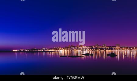 Die Lichter der Stadt Porto spiegeln sich auf dem Fluss douro mit dem lila Abendhimmel im Hintergrund und schaffen eine wunderschöne und ruhige Stadtlandschaft Stockfoto