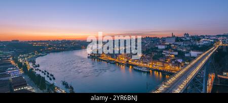 Farbenfroher Sonnenuntergang, der die Brücke dom luis i und den Fluss douro beleuchtet und porto und vila nova de gaia verbindet, bietet einen atemberaubenden Panoramablick Stockfoto