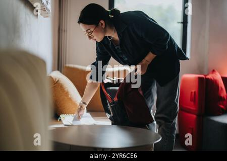 Junge Studentin organisiert Lernmaterialien im gemütlichen Wohnzimmer Stockfoto